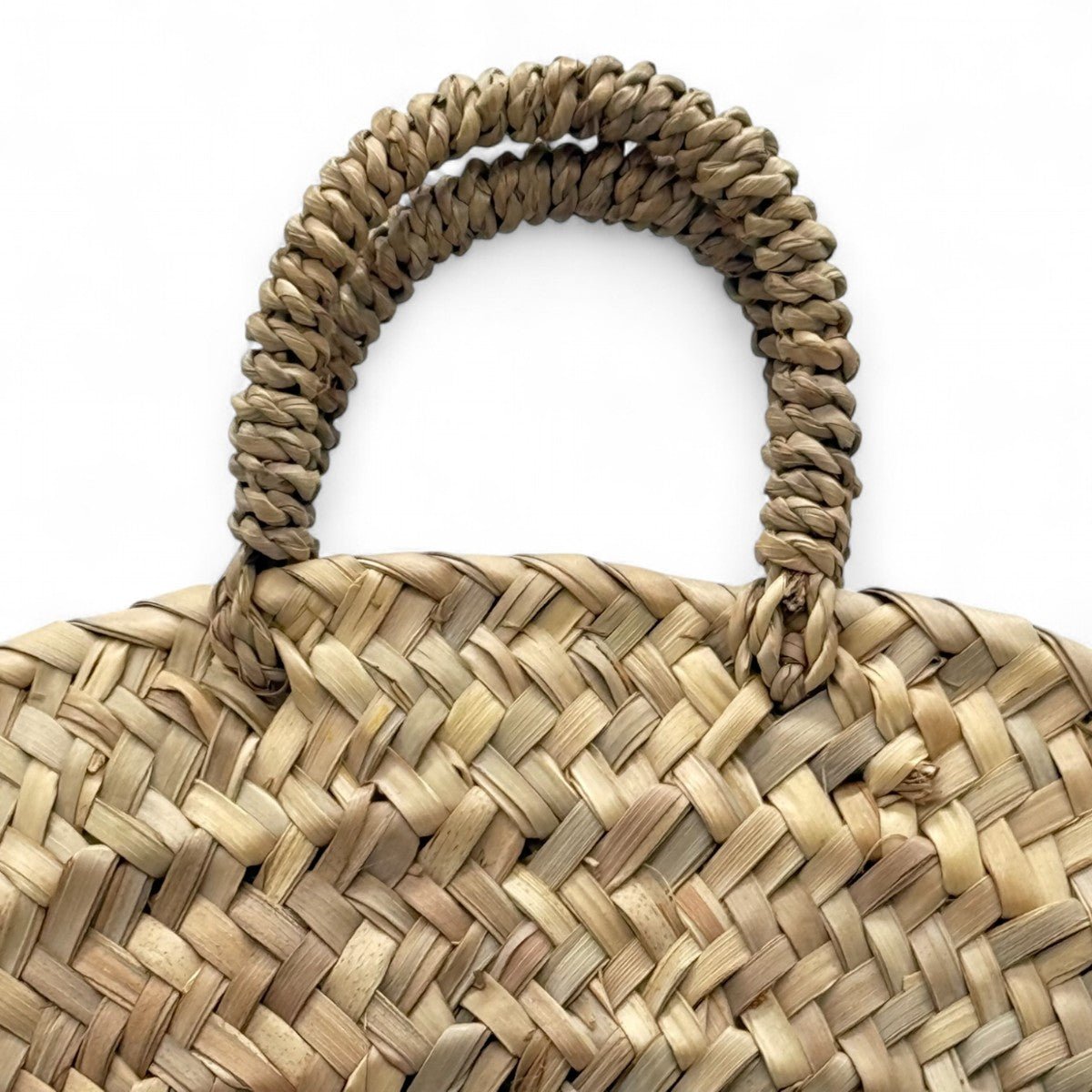 Profilo della borsa rotonda in paglia che ne mostra lo spessore e la tracolla.