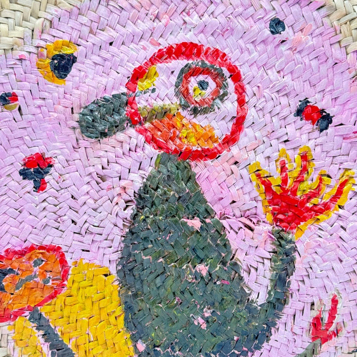 Primo piano del dipinto in stile Miró sulla borsa rotonda in paglia.