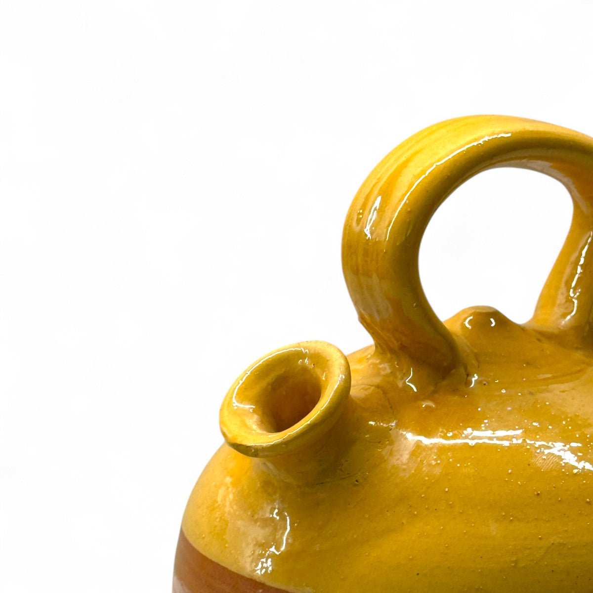 Il botijo vintage spagnolo accanto a un libro per mostrare le sue dimensioni.