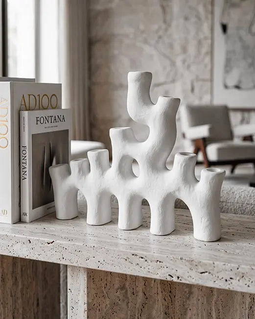candelabro di design in ceramica bianca sopra una mensola in travertino