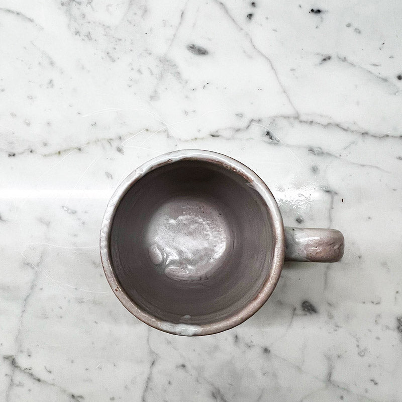 Una delle tazze della coppia blu e cacao piena di caffè, mostrando la sua capienza.