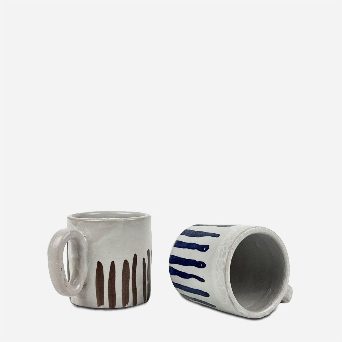Coppia di tazze blu e cacao in ceramica artigianale, una con pennellate blu e l'altra color cacao.