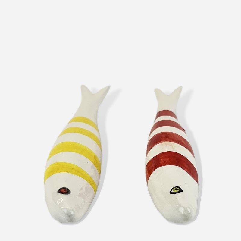 Pesci in ceramica colorati che decorano la parete di un bagno a tema marino.