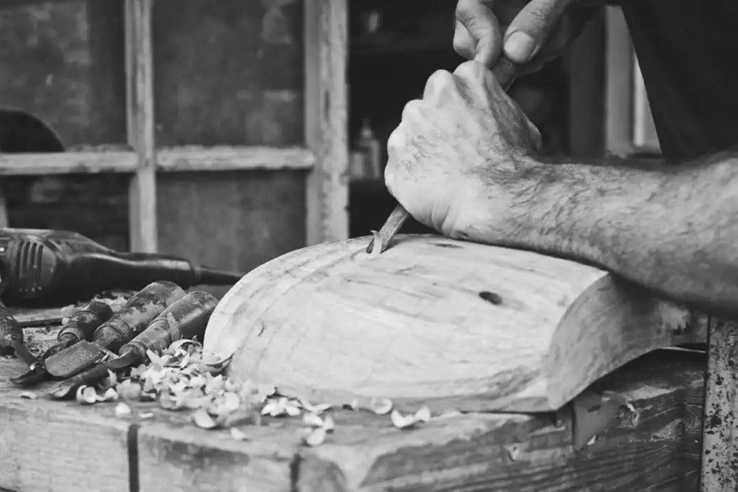 Dettaglio delle mani di Estebanland che utilizzano uno scalpello su un blocco di legno.