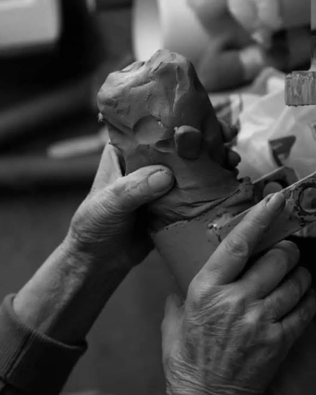 Primo piano di mani che modellano la terra, simbolo del processo creativo artigianale e della manipolazione della materia.