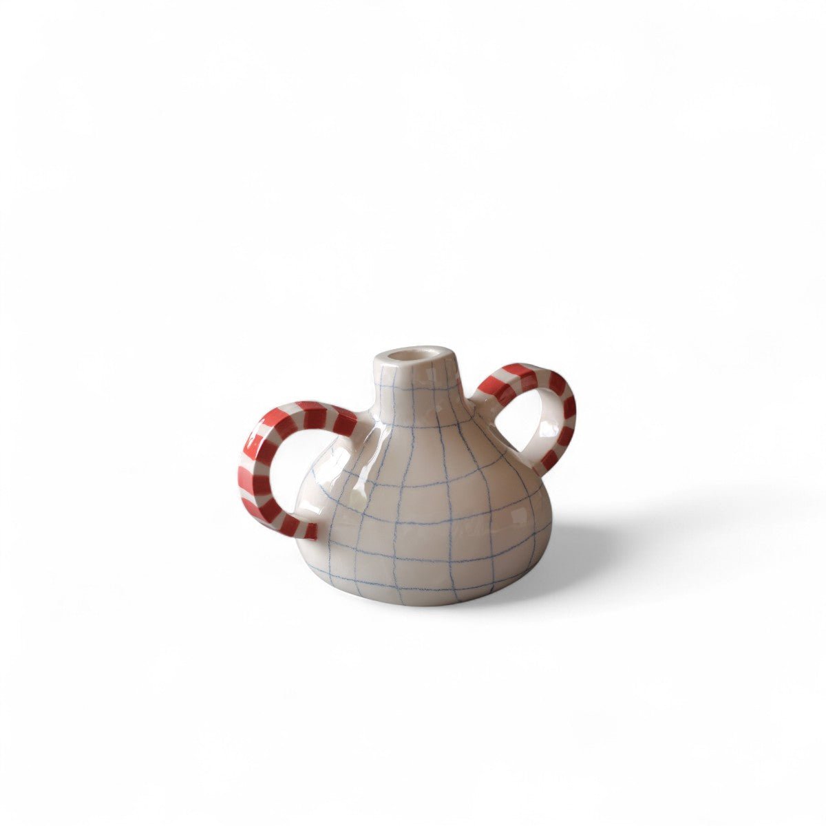 Il vaso in ceramica decorato a mano esposto su una mensola bianca tra alcuni libri.