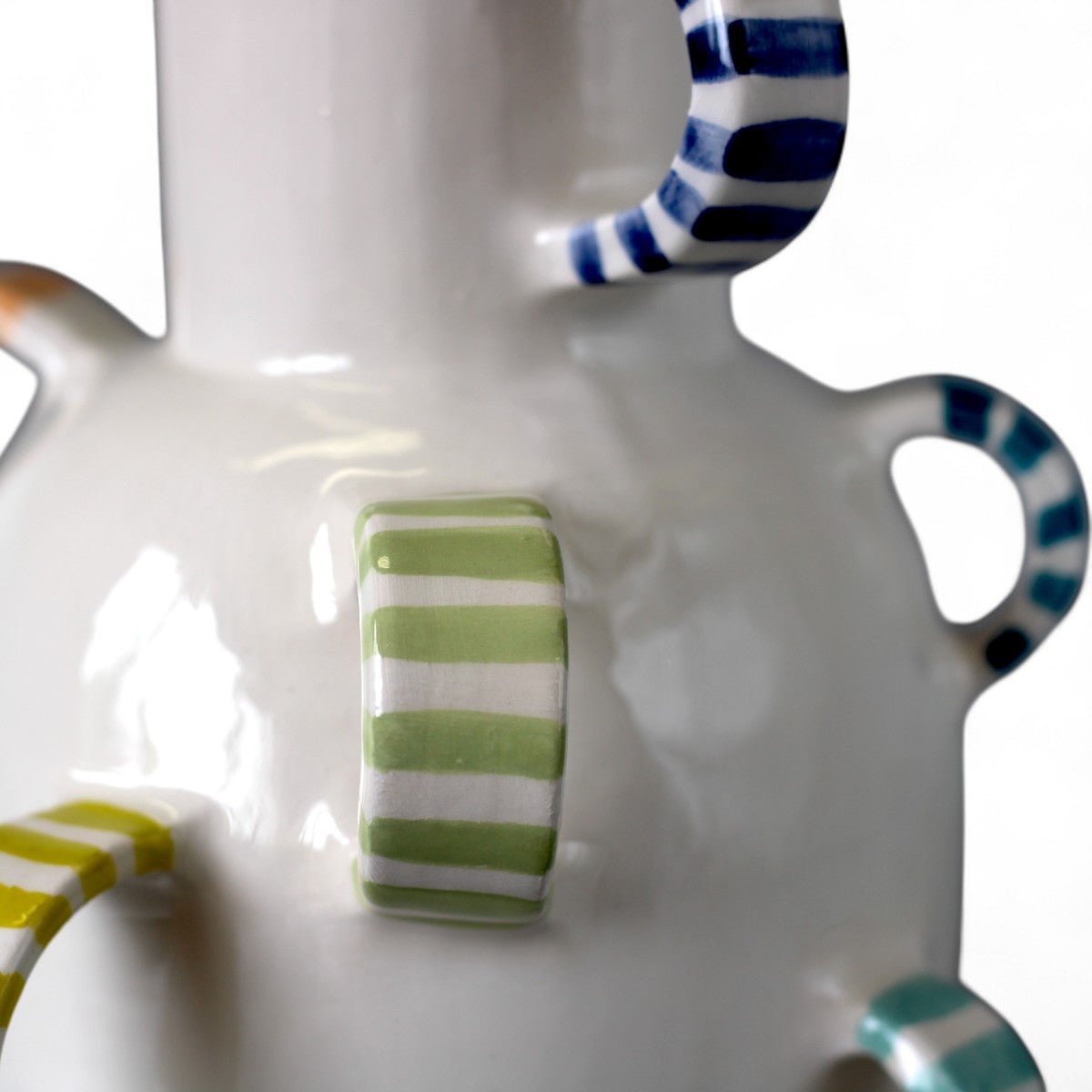 Mano che posiziona il vaso in ceramica colorato su un tavolo di design.