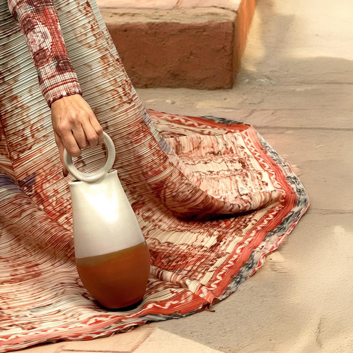 Modella che indossa il kimono plissettato Blush Horizon sopra un abito elegante.