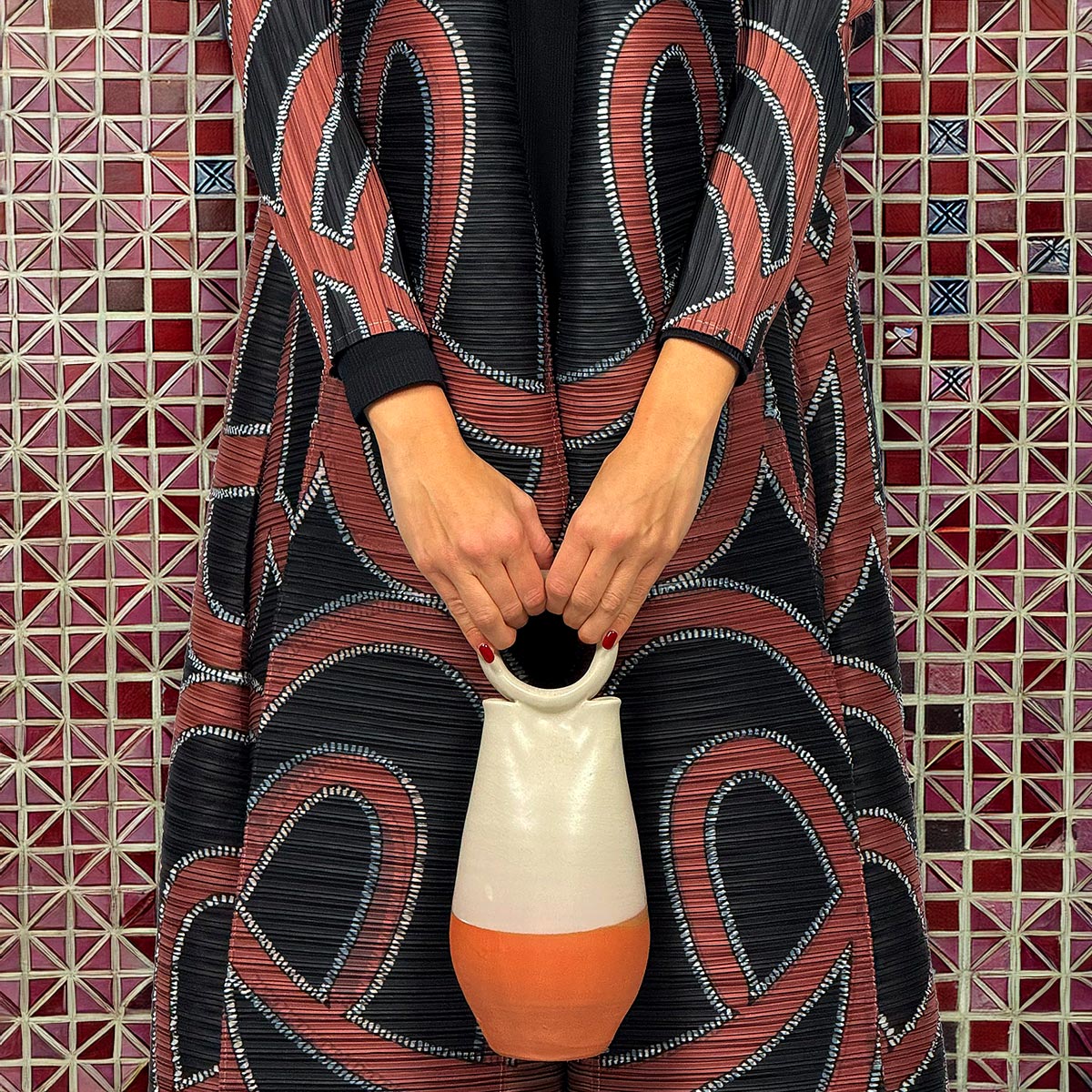 Primo piano del tessuto plissettato del kimono Eternal Maze con i suoi toni caldi della terra.