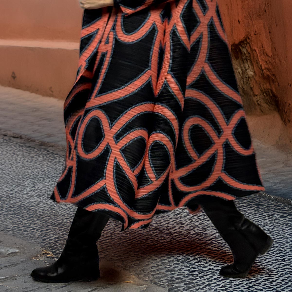 Primo piano del tessuto plissettato e del motivo a linee arancioni del kimono Sunset Orbit.