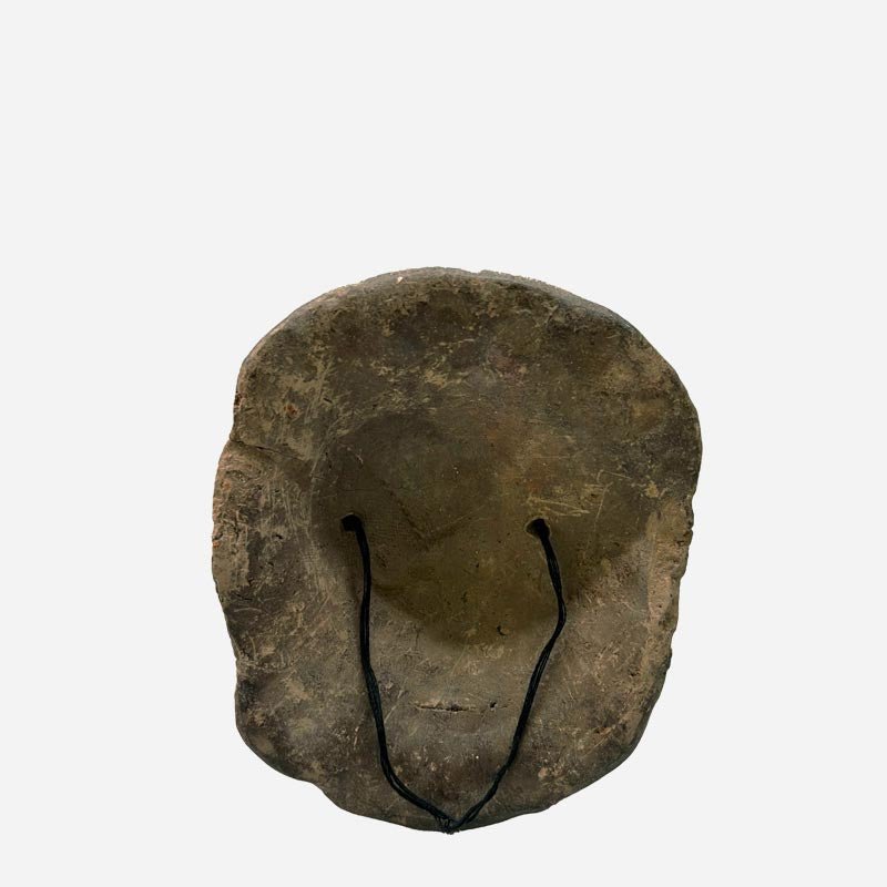 La Maschera Volto Arcaico tenuta in mano per mostrare la texture della terracotta grezza.