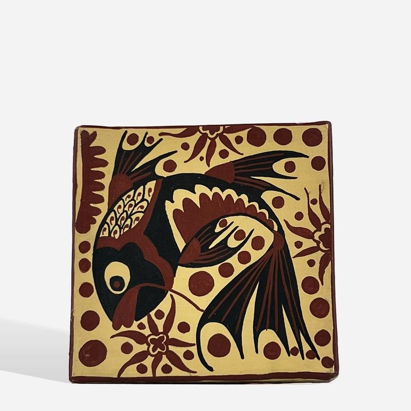 Mano di un artigiano che dipinge i dettagli di una Mattonella Socarrats con ocra rossa.