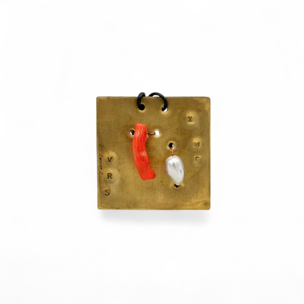 Incisioni enigmatiche di lettere e simboli sulla placca in ottone del Monile Corallo di Luna.