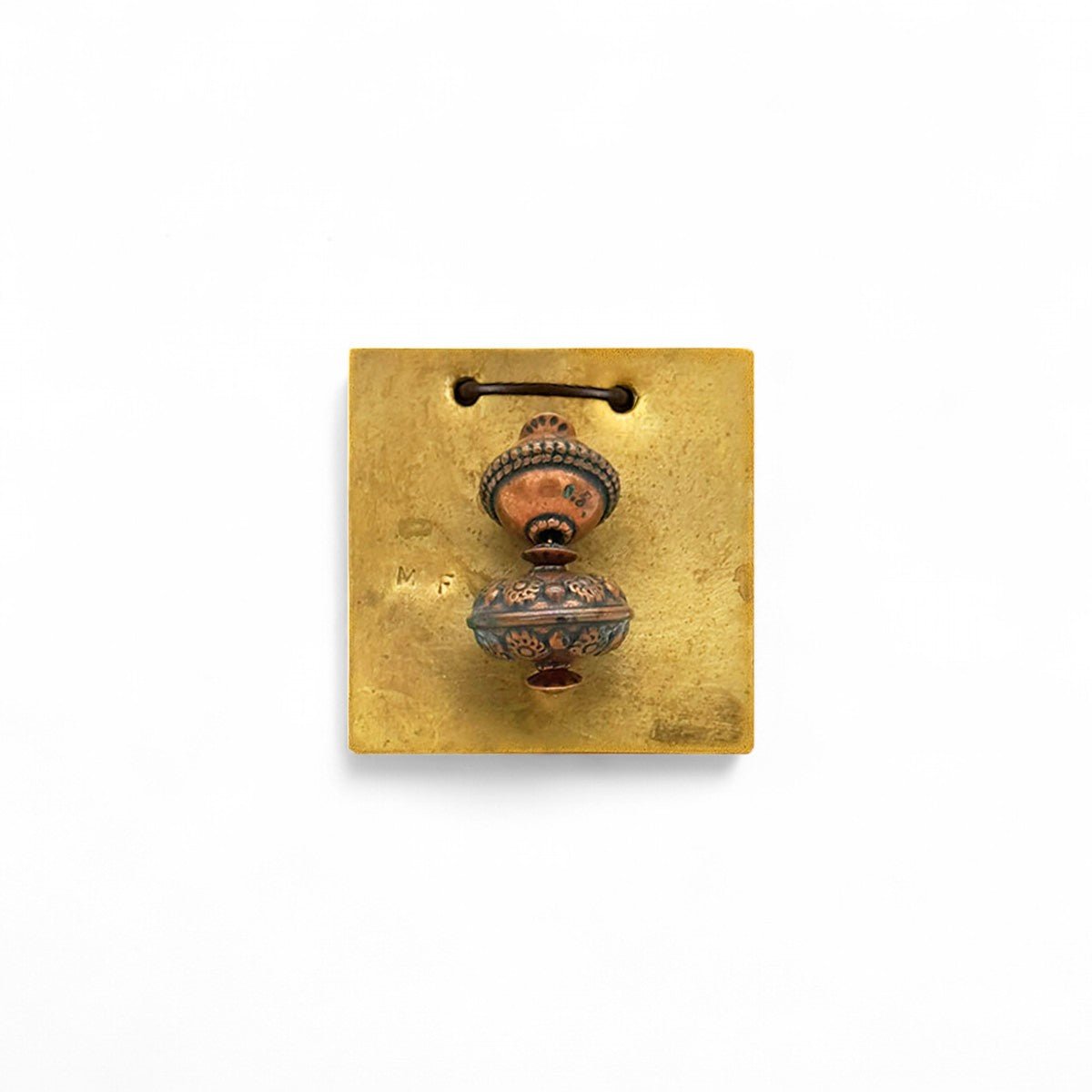 Dettaglio della placca in ottone minimalista e della sua finitura calda e opaca.