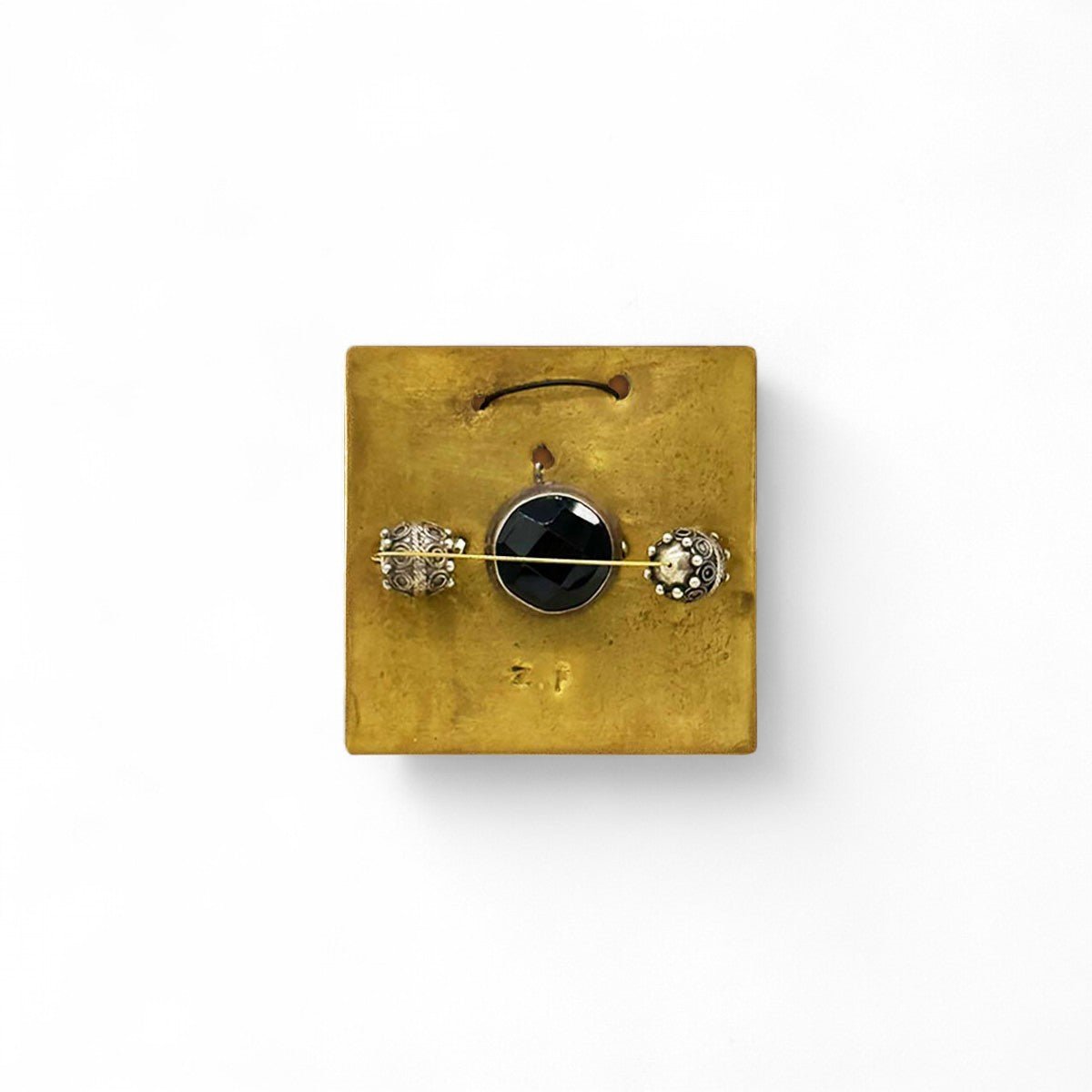 Particolare del sottile filo fuso alla placca in ottone del Monile Eclissi Errante.