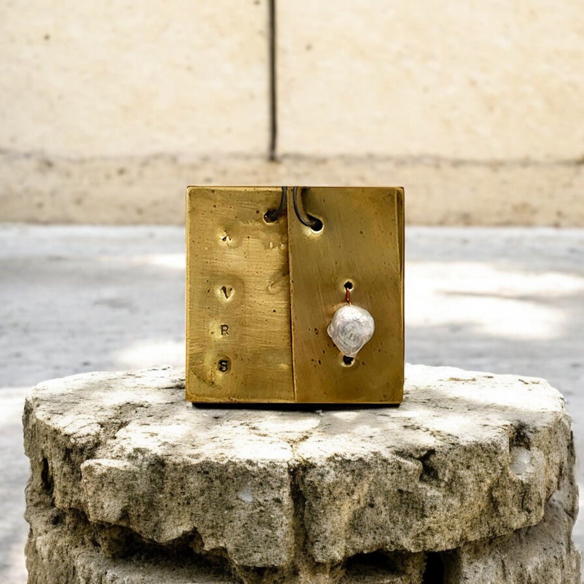 Dettaglio delle incisioni evocative sulla placca in ottone lavorata a mano del Monile Perla Nomade.