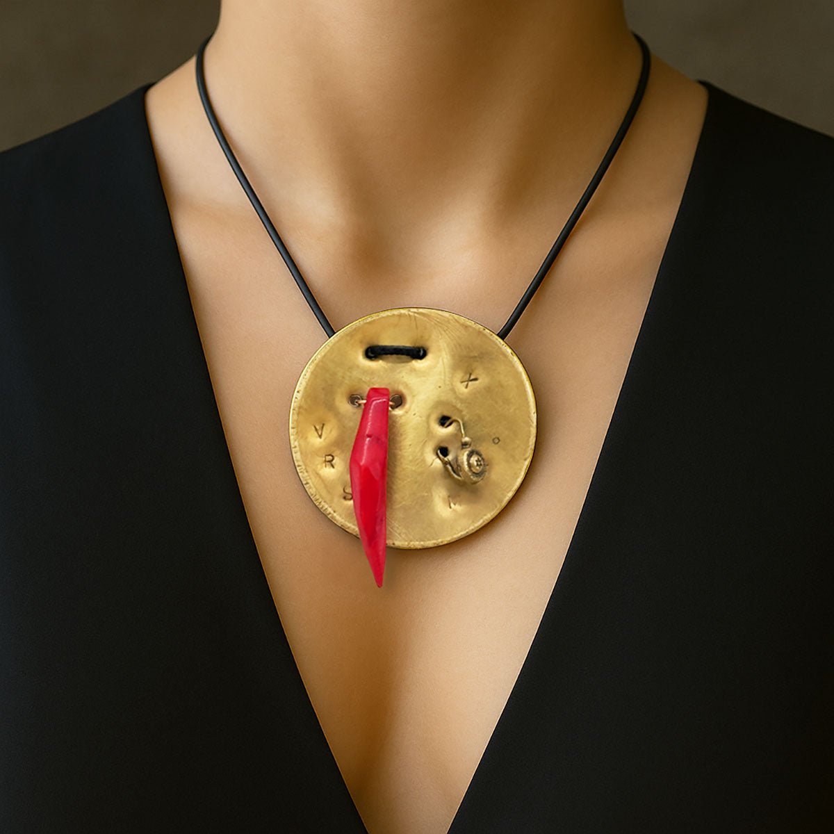 Monile Rosso Talismanico, gioiello artigianale con corno rosso e placca in ottone inciso.