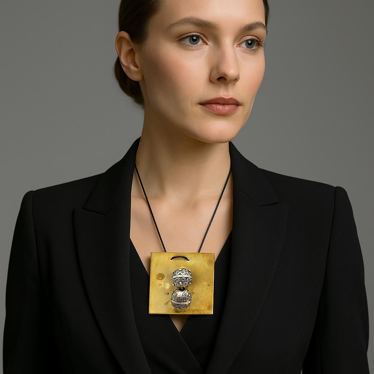 Primo piano delle sfere in metallo del monile Sfere Gemelle che mostrano le fini incisioni a spirale.