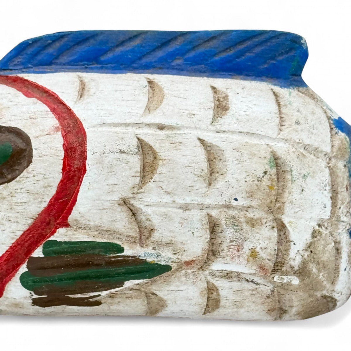 Mano che posiziona la scultura pesce in legno su una pila di libri.