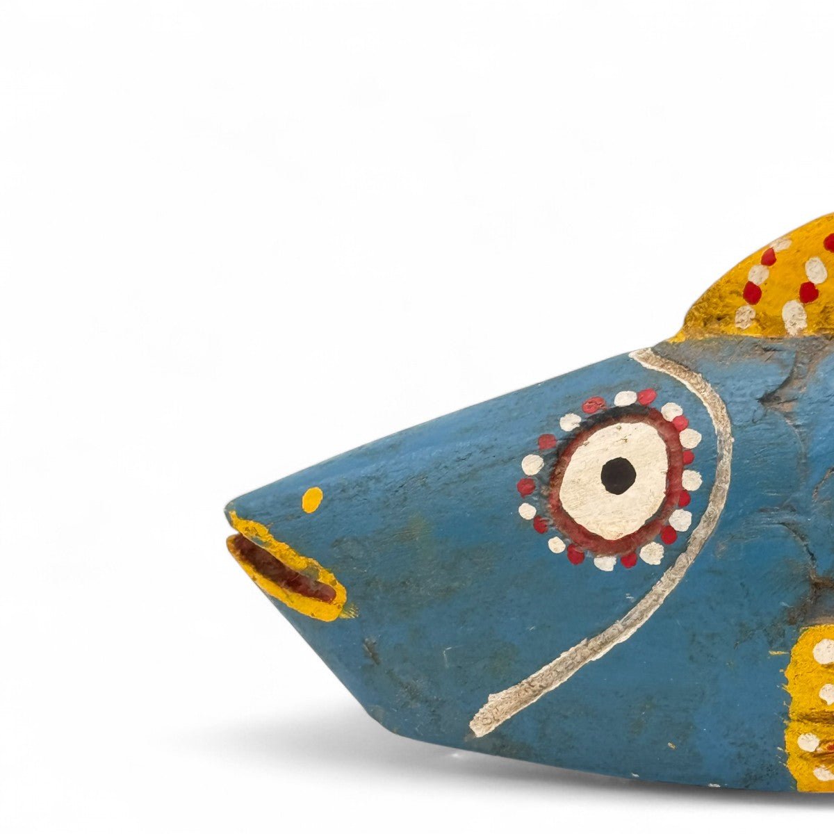 Dettaglio della vernice consumata e dei punti ocra sulla scultura pesce in legno.