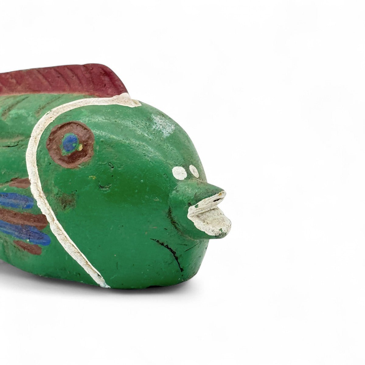 Dettaglio della vernice consumata e dei colori vivaci sulla scultura pesce in legno.