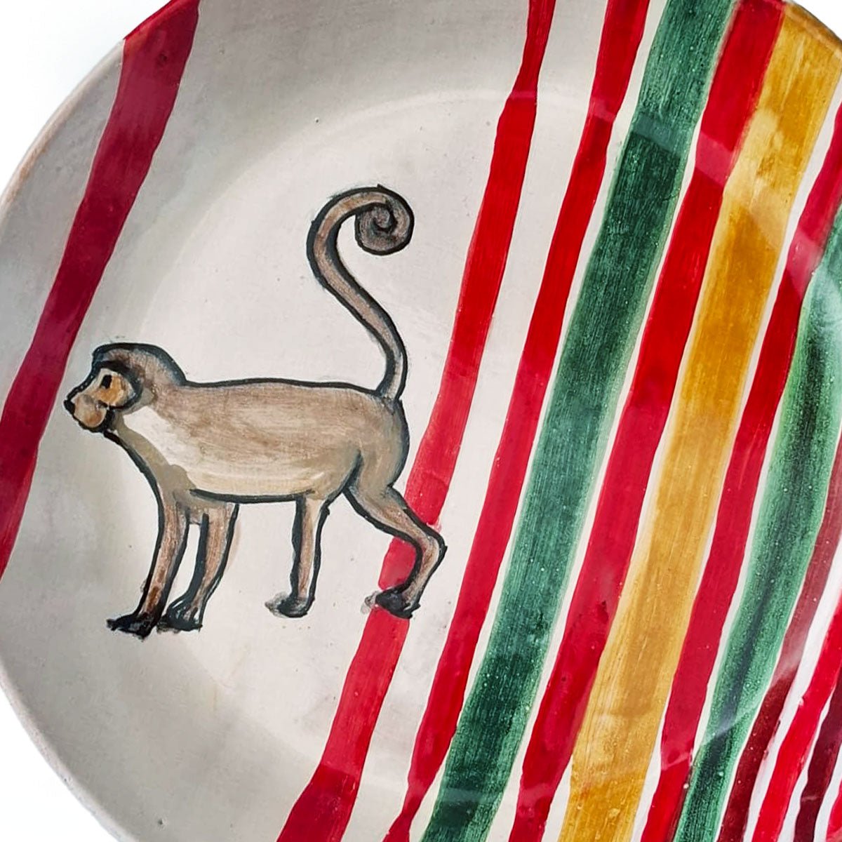 Dettaglio del fondo dinamico con strisce diagonali rosse, verdi e ocra del piatto.