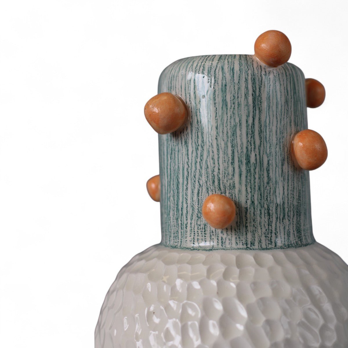 Mano che posiziona il vaso in ceramica rosso su una pila di libri d'arte.