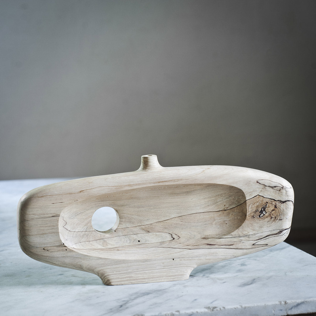 Dettaglio del foro passante che attraversa la scultura in legno di acero, creando un vuoto.