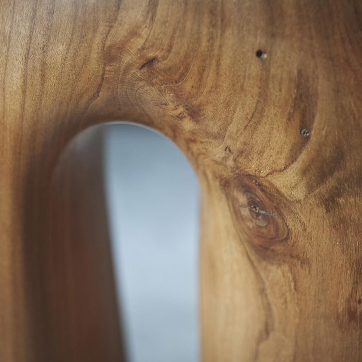 Primo piano della superficie levigata e delle venature calde del legno di ciliegio della scultura.