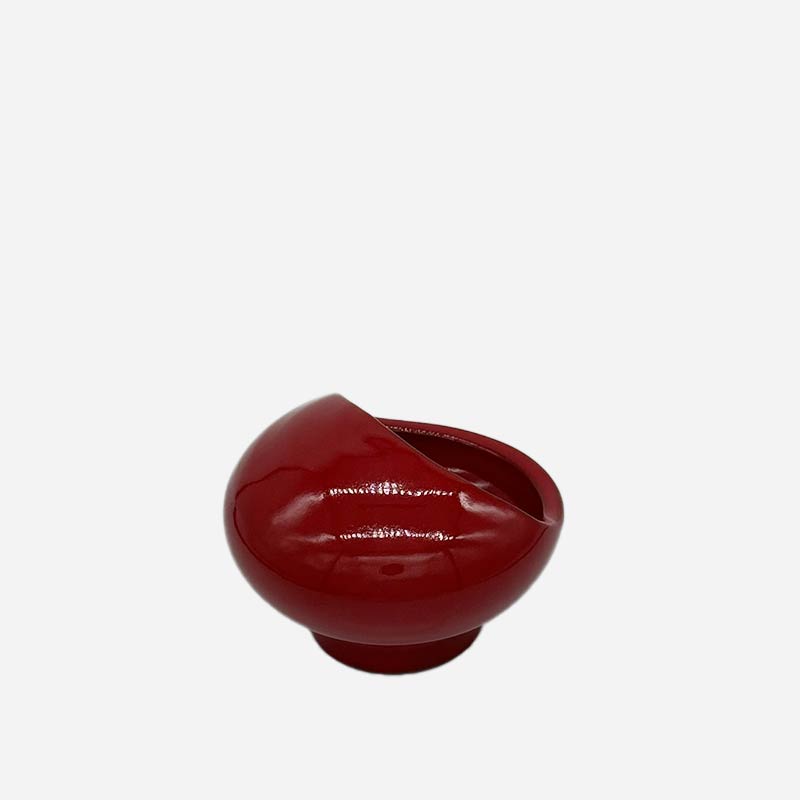 La Scultura Rosso Ember utilizzata come svuotatasche di design su una scrivania in legno.