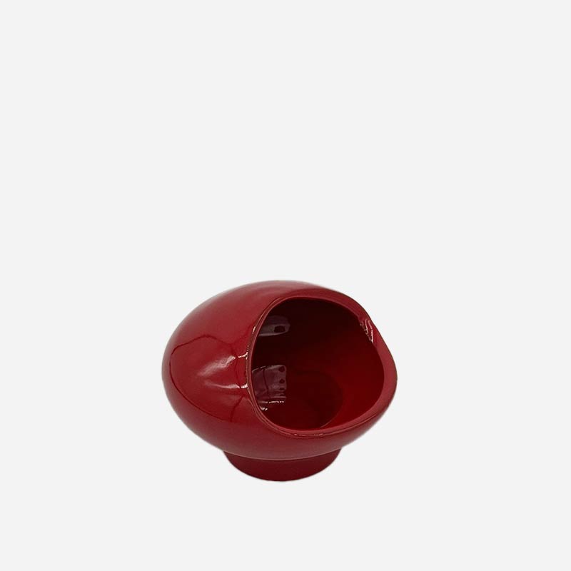 Mano che posiziona la Scultura Rosso Ember accanto a una pila di riviste di design.