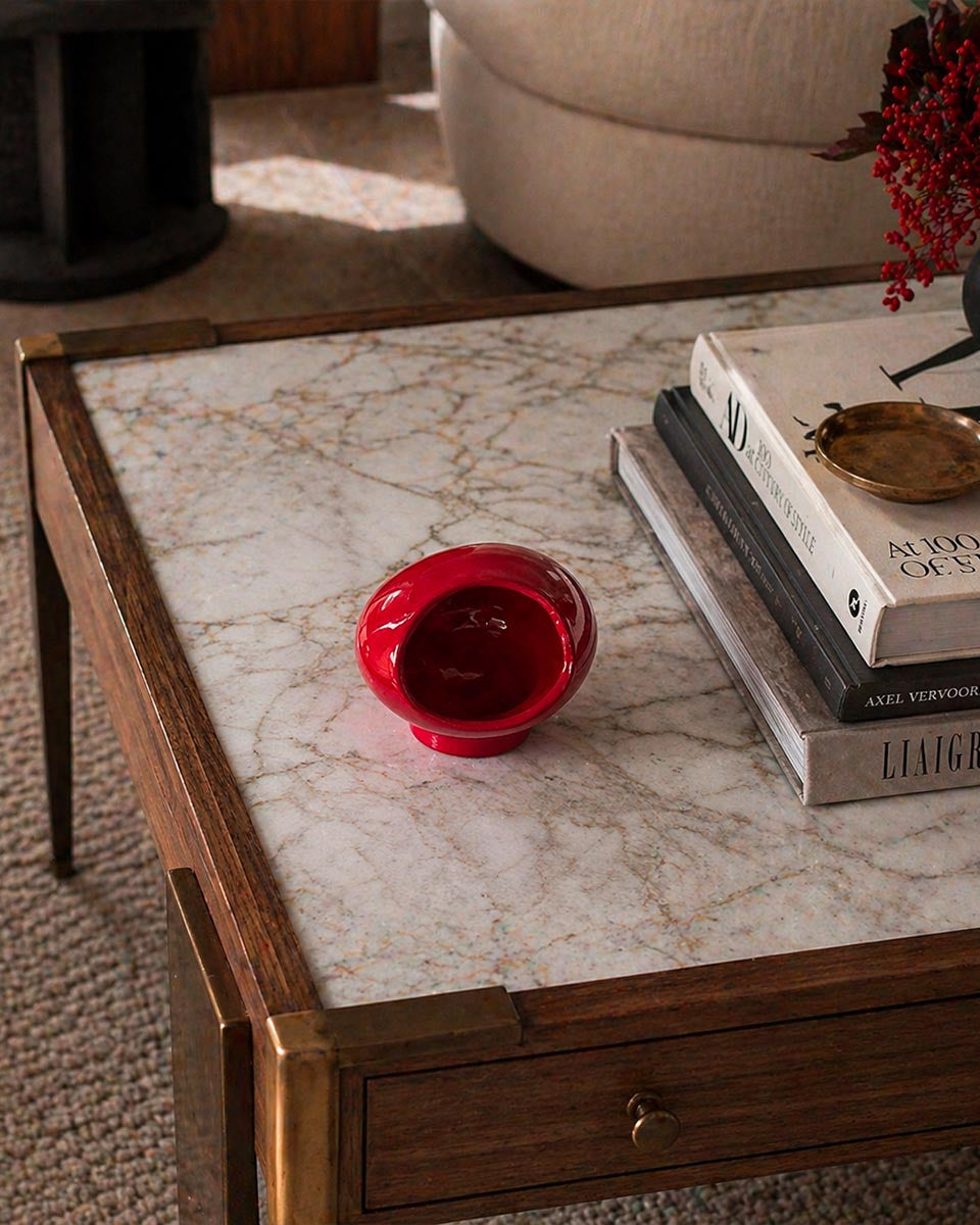Primo piano del colore vibrante della Scultura Rosso Ember, su tavolino in noce canaletto e marmo calacatta, con libri di design