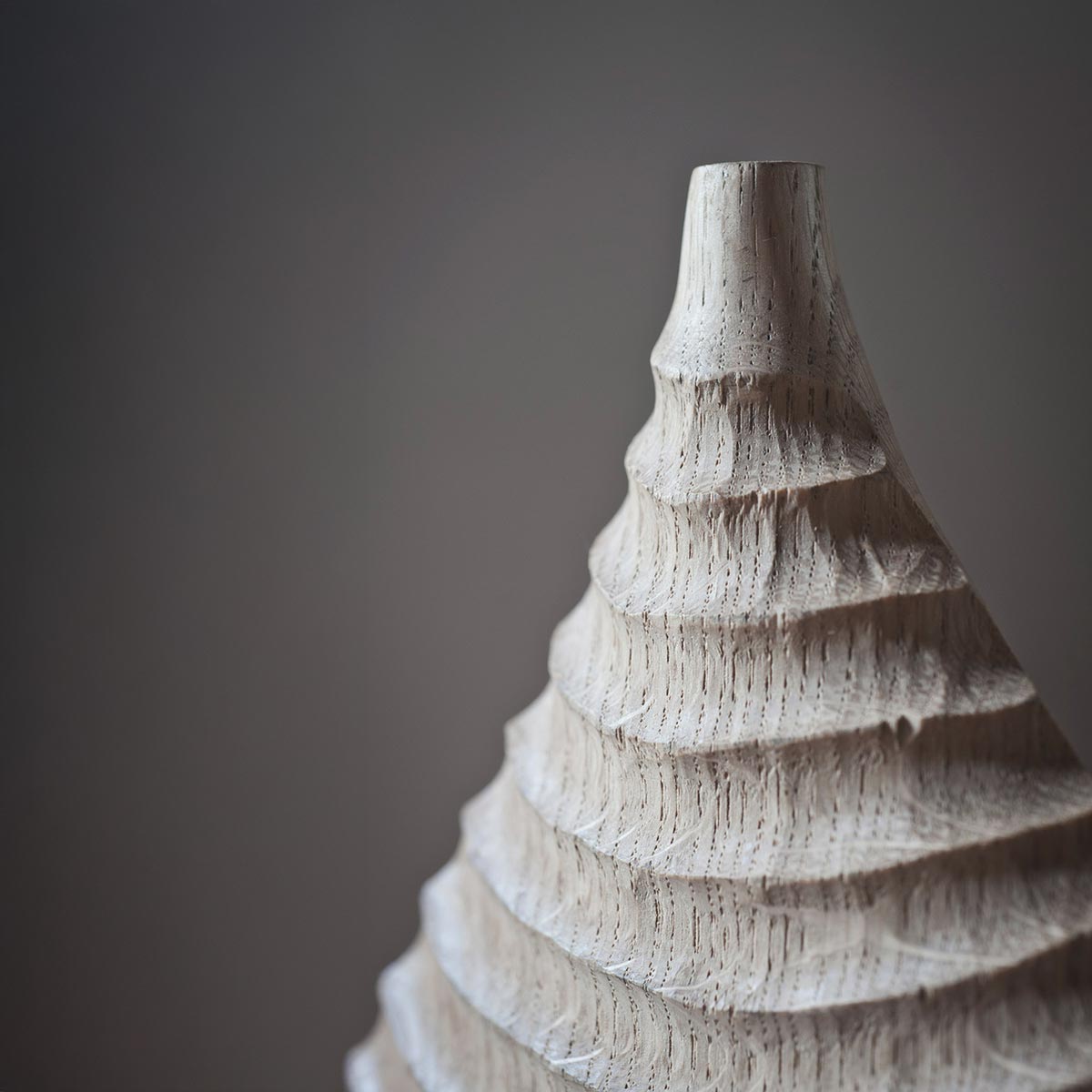 Primo piano della venatura del legno di rovere e delle incisioni sulla superficie della scultura.