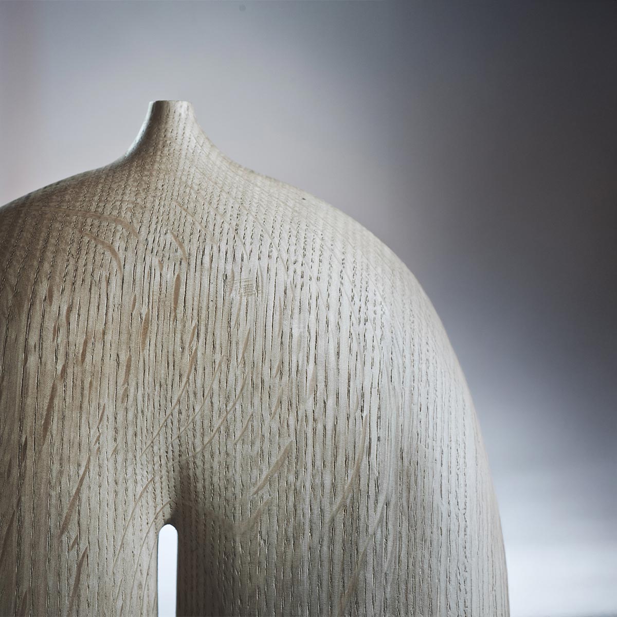 Primo piano della superficie levigata e delle incisioni sul legno di rovere della scultura.