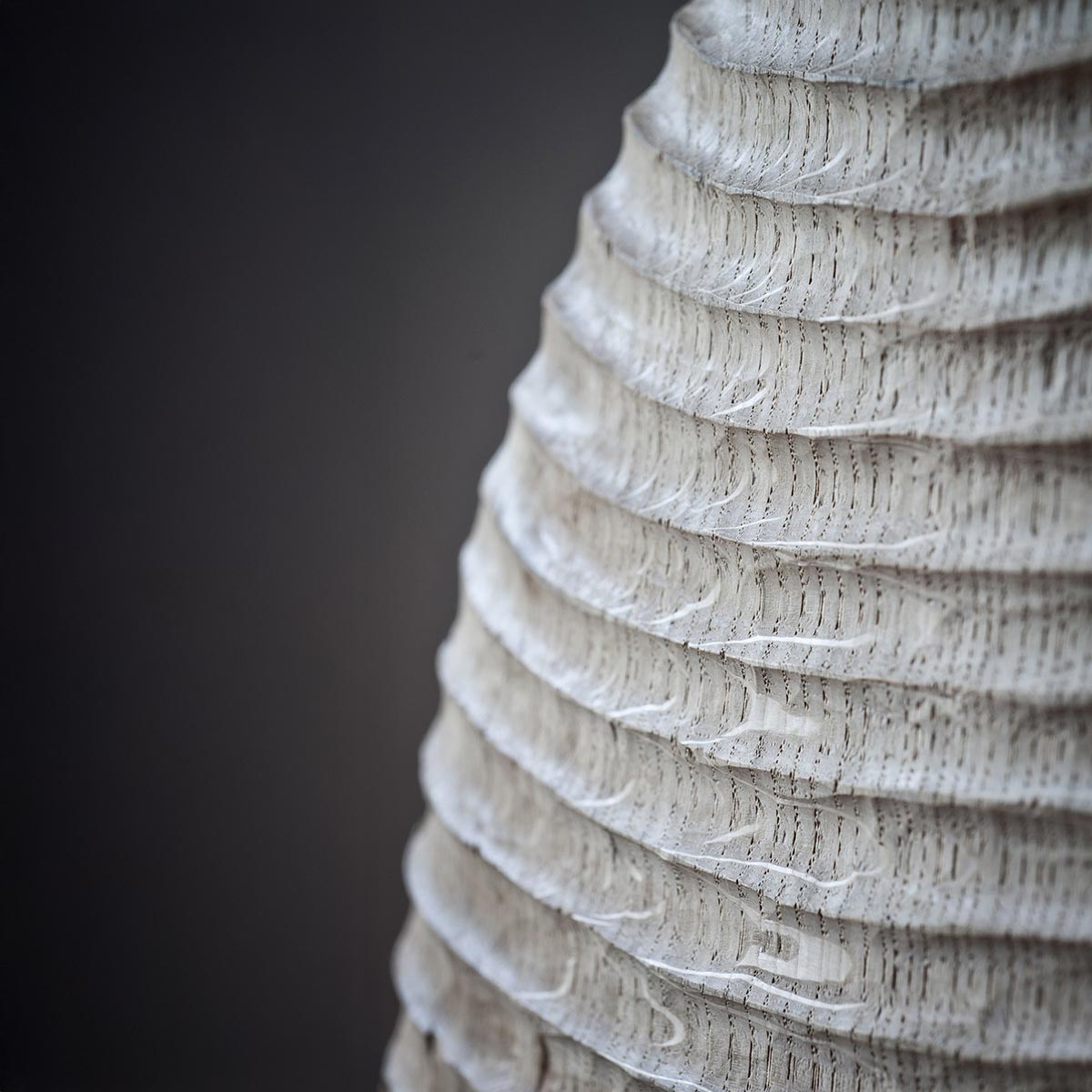 La scultura in legno di rovere esposta da sola su una mensola, mostrando la sua forma a fiamma.