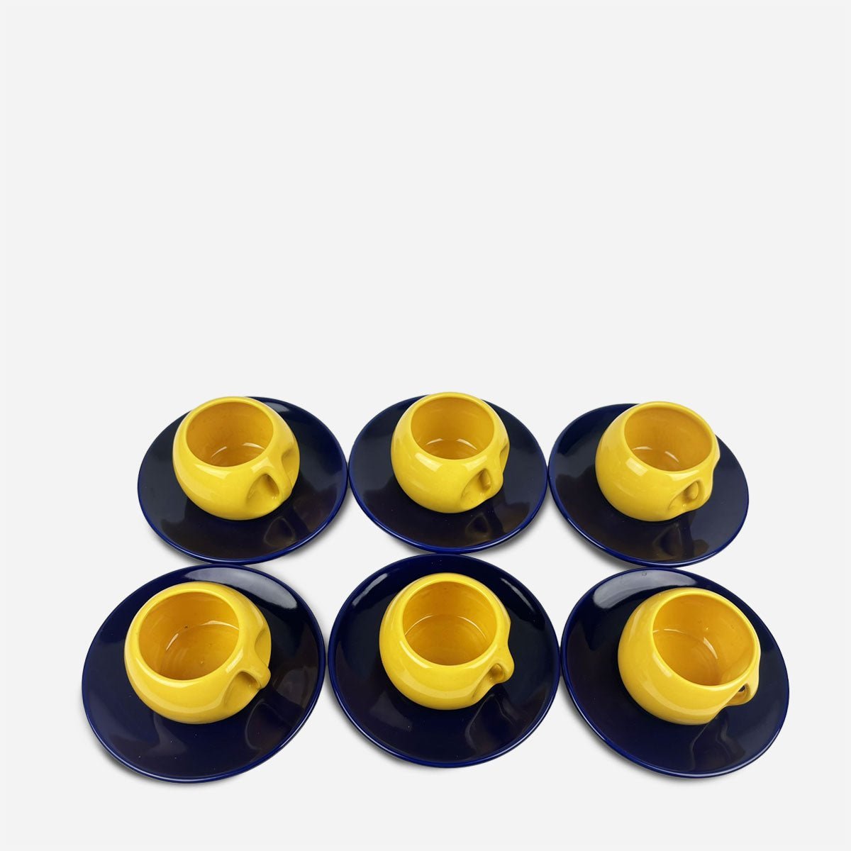 Mano che versa il tè dalla teiera blu e gialla del Set da tè Majorelle in una delle tazze.