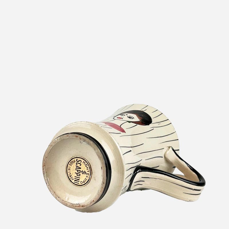 Mano che versa la limonata dalla caraffa vintage in uno dei bicchieri coordinati.