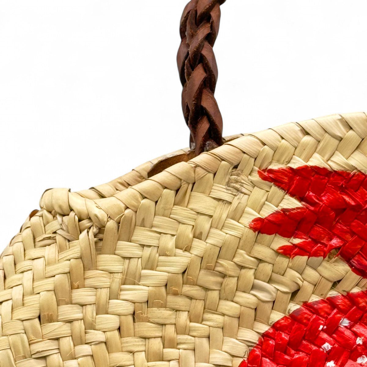 Profilo della borsa rotonda in paglia che ne mostra la forma e la pittura laterale.