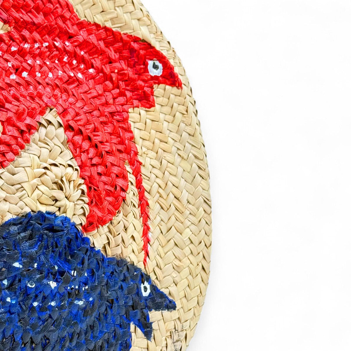 La borsa dipinta a mano I Pesci Combattenti posata su un muretto con vista mare a Taormina.