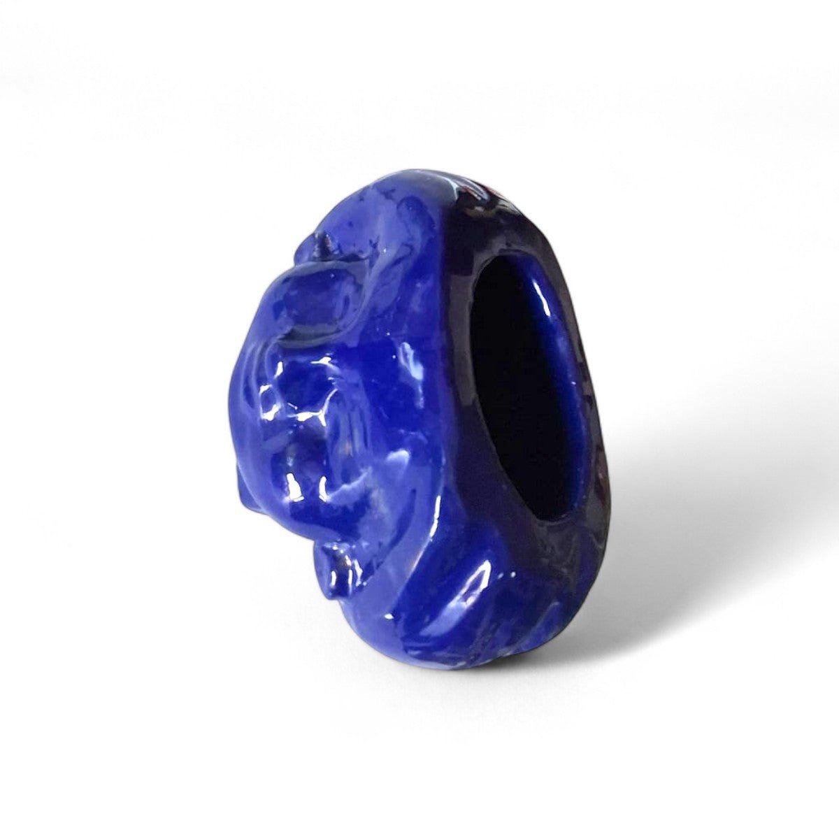 La scultura testa ceramica accanto a una candela per un confronto dimensionale.