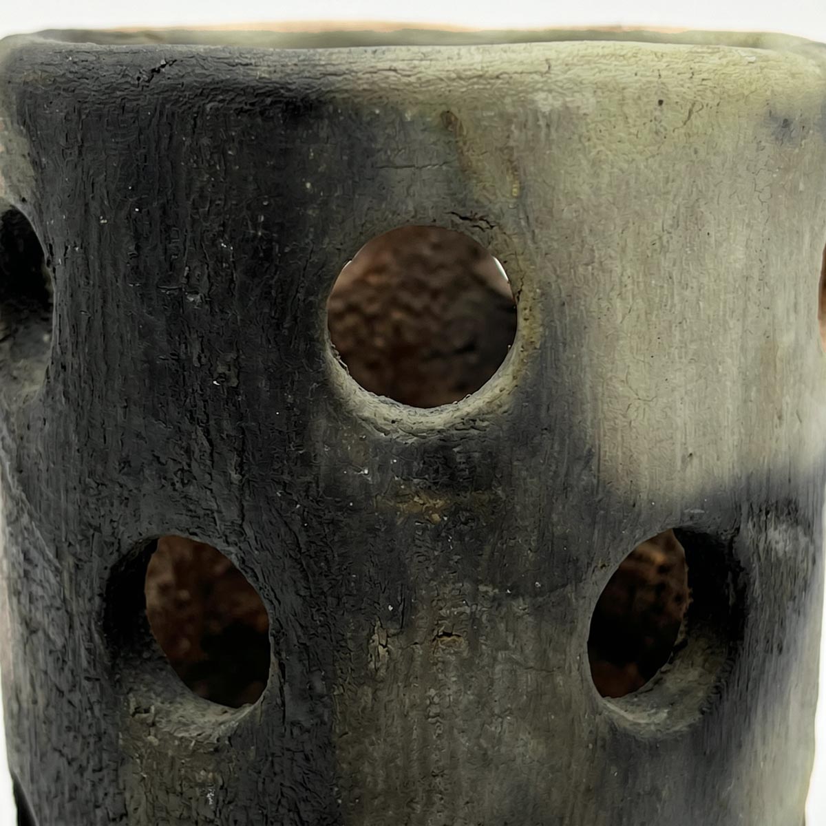 Violenta fiammata nero carbone sulla superficie color cenere chiara del vaso lanterna patrimonio UNESCO.