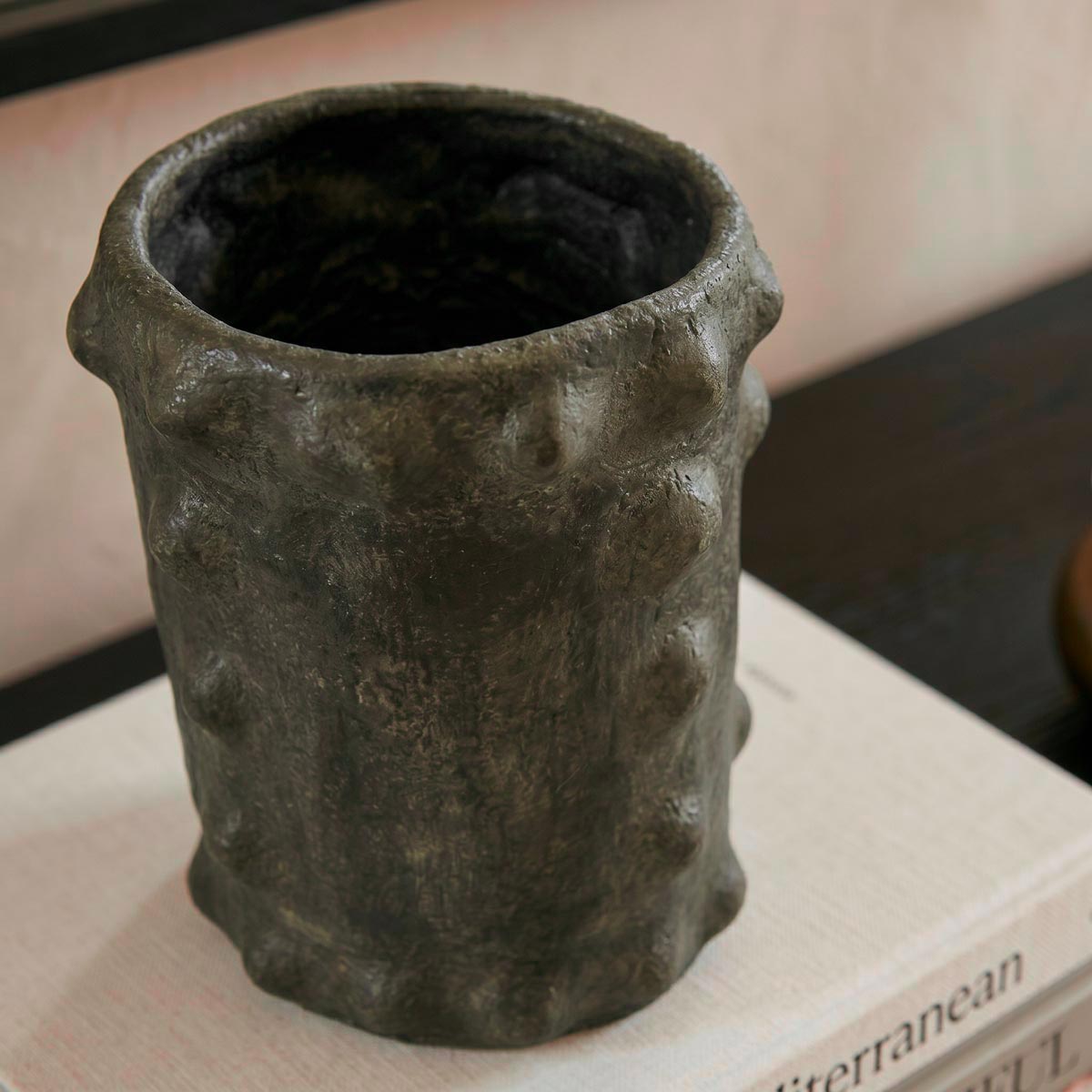 Texture porosa e finitura nero metallizzato con sfumature di cenere, frutto della cottura ancestrale sotto paglia.