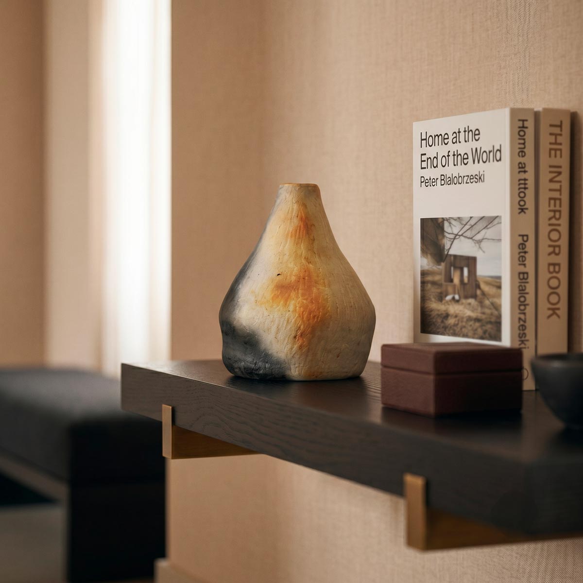 Dettaglio della fiammata nera di fumo che taglia la base del vaso scultoreo in terracotta naturale.