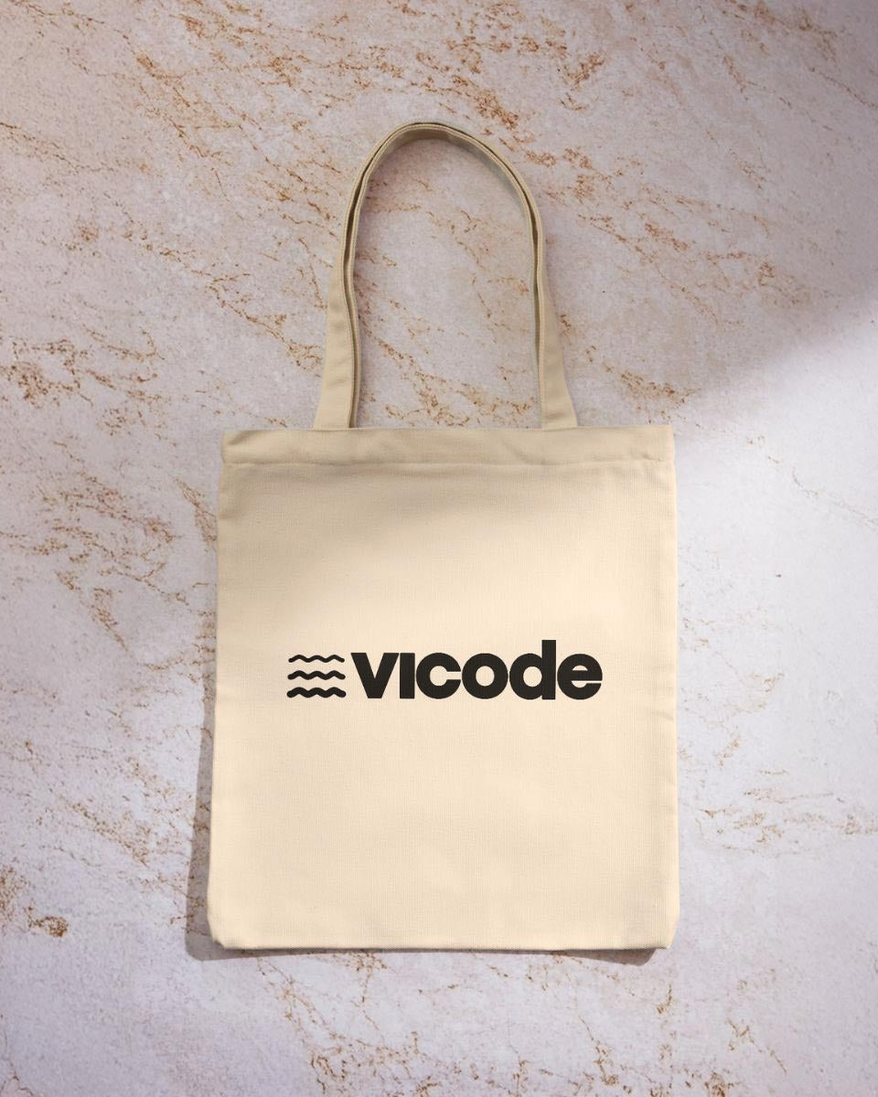 Tote bag in cotone Vicode con logo nero stampato su tessuto color naturale.