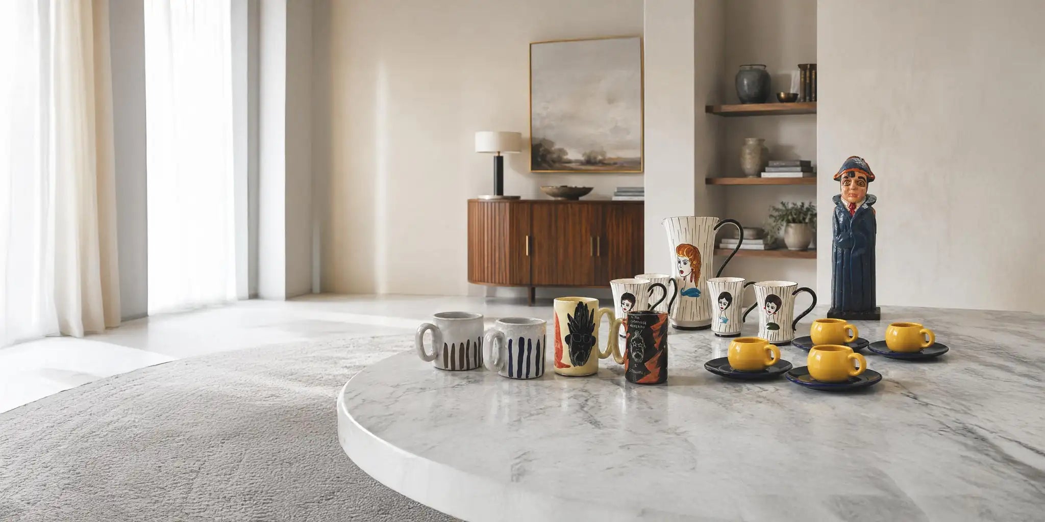Selezione di accessori per la casa in ceramica artigianale, con tazze, boccali, set da tè e caraffa vintage su un elegante tavolo in marmo.