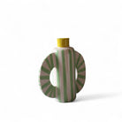 Dettaglio delle linee verdi verticali e dei ventagli laterali del vaso scultoreo.