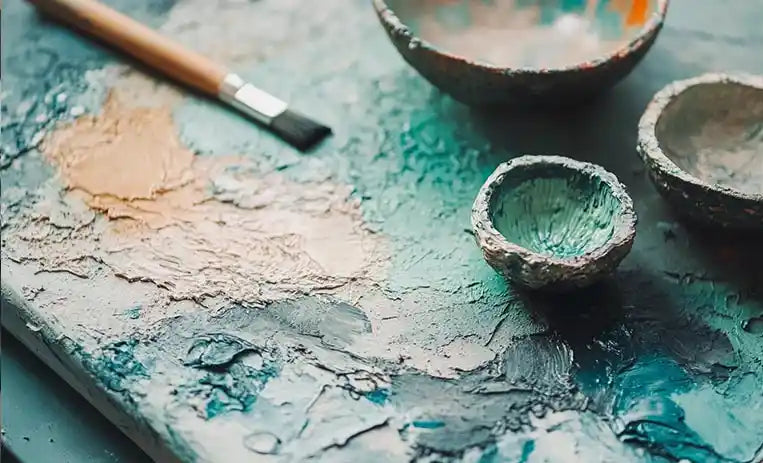 Tavolozza d'artista con pennelli e colori a olio materici nelle tonalità del blu e dell'ocra.