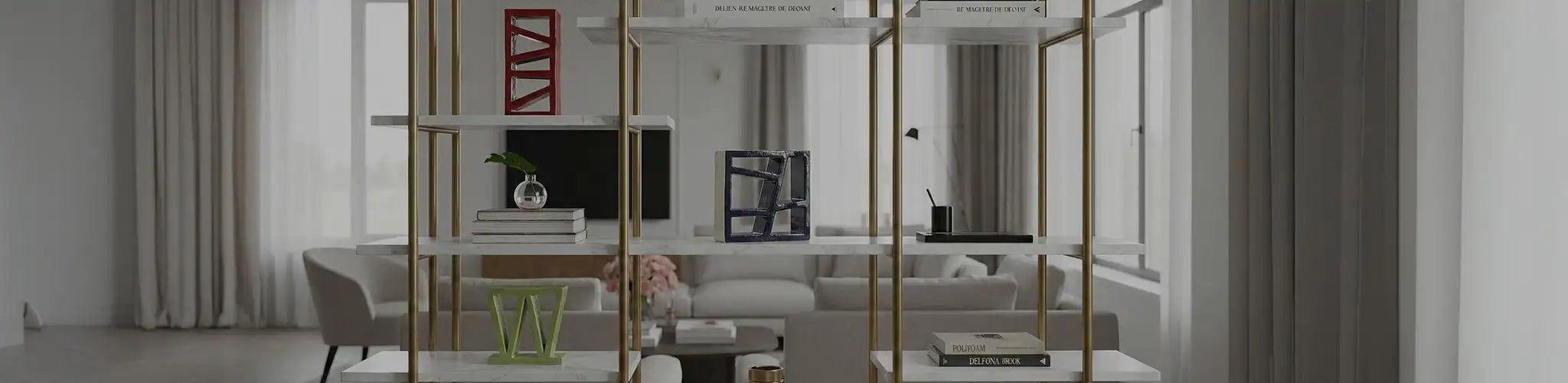 Ampia veduta di una lussuosa libreria a giorno con struttura in ottone e ripiani in marmo bianco, situata in un luminoso living moderno. Espone tre distinte sculture geometriche in ceramica lucida (rossa verticale, blu quadrata, verde a forma di W), alternate a pile di libri di design e vasi minimalisti.