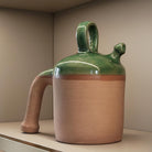 Dettaglio della base in terracotta nuda e porosa del botijo verde decorativo.