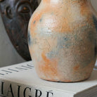 Dettaglio delle sfumature arancio e fumo sulla brocca artigianale in ceramica chiara